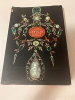Front cover of the book showing the title and detailed jewelry artwork on the dust jacket with some damage to edges.