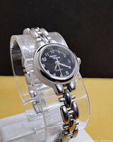 Side angle view of the ladies petite quartz watch displaying the linked silver-tone metal bracelet and black dial with white numerals.