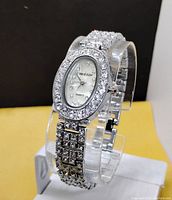 Front angled view of the ladies quartz watch on display stand, showing the sparkly rhinestone bezel and bracelet, and the white oval dial with brand name Côte d'Azur and quartz movement.