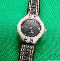 Close-up of the round silver-tone watch face and black dial with Caprice branding and water resistance information.