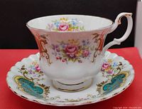 Royal Albert teacup and saucer side view showing floral design with pink roses and gold ornate detailing on white bone china.