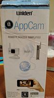 Photo of the product box front showing the Uniden AppCam logo, remote access with Wi-Fi capability, and visual depiction of the surveillance camera and router.