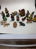Wide group shot of entire nativity set showing various figures including animals and human characters on a white backdrop.