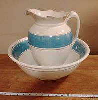 Front view of jug inside basin, showing jug's wide handle, blue band, and repositioned measuring tape indicating size.