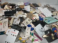 View showing a large pile of new earrings on branded and unbranded cards, including studs, hoops, and dangles.