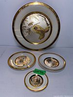 Full view of all four decorative plates showing the large charger and three smaller plates arranged on a table.