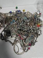 Top view showing the mix of tangled silver-tone chains, pendants, and some colorful accents in blue and red enamel with faux pearls and multiple types of links.