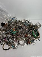 Large pile of assorted mixed jewelry pieces showing mainly bracelets, bangles, and necklaces with colored beads and metal designs.