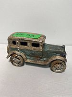 Side view of antique cast iron toy car showing worn paint, detailing on wheels and body, and patina.