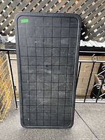 Top view of black folding table showing the grid textured surface with visible scratches and a green price sticker.