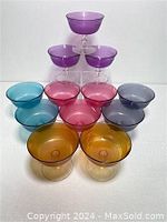 Photo showing multiple champagne saucers arranged in a pyramid shape, colors purple, pink, blue, amber, and gray visible.