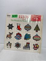 Front cover of vinyl record showing Christmas themed artwork with ornament illustrations and Elvis Presley branding.