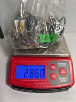 Bag with a large assortment of costume jewelry on a digital scale showing weight 2.860 pounds.