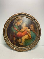 Front view of the round framed artwork showing Madonna holding Child with a third figure to the right in classical style.