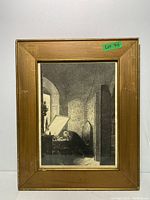 Front view of framed Rembrandt print depicting an interior scene with a person near a window.