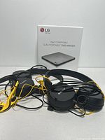 Overview of two pairs of wired headphones and the LG portable DVD writer box