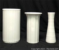 Front view of three white ceramic vases arranged side by side against black background showing their shapes and textures.