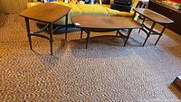 Three wooden tables: one coffee table center, two side tables flanking, on carpet
