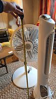 White pedestal fan with round base; measuring tape shows about 32 inches tall