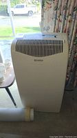 Full front view of the beige Kenmore air conditioner dehumidifier unit showing grill and overall body shape positioned near a window.
