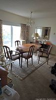 Wide shot of oval dining table set up in living room with one leaf inserted and five wooden chairs around