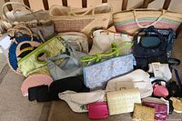 Photo of the complete collection of 17 assorted purses and handbags on the floor showing variety of sizes, colors, and materials.