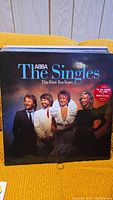 Photo showing ABBA The Singles: The First Ten Years vinyl record cover with four band members dressed formally.