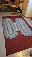 Photo showing all rugs together with the braided rugs arranged on top of the red rectangular rug.