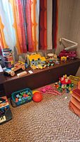 View of three shelves with various vintage toys including a pressed tin Tonka truck, toy houses, figurines, and toy cars on a carpeted floor
