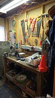 Workbench and pegboard showing assorted tools and hardware items hung or placed on bench surface.