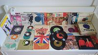 Wide view of multiple vinyl records and album sleeves laid out on a surface, showing a variety of styles and labels.