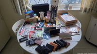 Wide view of table covered with assorted wallets, stationery items, personal care items, and small accessories.