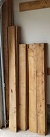 Photo showing vertical stack of cedar boards of various lengths leaning against a wall; includes long and mid-sized boards consistent with 1"x6" and 1"x4" dimensions