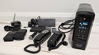 Photo showing CyberPower UPS, two corded landline phones, USB keyboard mouse switch, and other cables/devices.