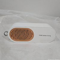 Front view of the white and brown TOBE Better Living fruit and vegetable cleaner showing its compact, vented design and keyring hole.
