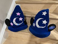 Blue plush Sorcerer Hat with silver crescent moon and stars, black mouse ears, stars are lit up pink/purple.