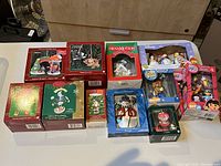 Photo showing 11 Christmas ornaments in original boxes and packaging, including Hallmark and Carlton Cards brands with detailed themes such as snowmen, nutcrackers, and holiday characters.