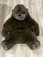 Top-down view of the stuffed gorilla lying flat on a wood floor showing the full body shape and colors.