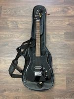 Full view of black WRW electric guitar on top of its black padded soft carrying case.