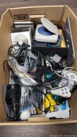 Overhead view of box filled with controllers, cables, light gun and electronics