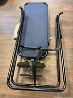 Top view of folded inversion table frame showing backrest, ankle foam pads, and metal frame.