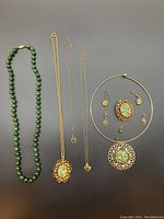 Full set showing all items including jade bead necklace, filigree pendants, earrings, and chain necklaces with jade chips