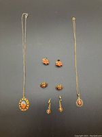 Full lot overview with both necklaces and all pairs of earrings displayed flat on dark background.