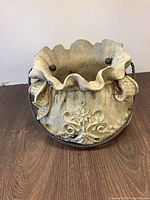 Front view of outdoor pot showing ruffled edges, floral design, and metal handle.