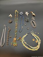 Top view of entire set with necklaces, bracelets, brooches, and earrings spread on a black surface.