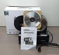 Photo showing the entire food slicer unit, original box behind it, and the instruction manual standing in front.