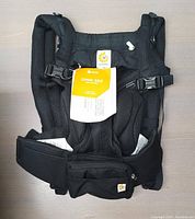 Top-down view of the black Ergobaby Omni 360 Cool Air Mesh baby carrier with attached tags and padded shoulder straps visible.