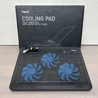 Havit laptop cooling pad with box behind, showing brand name and product compatibility up to 17 inches.