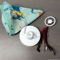 Top view of all items including fabric tent cover, white motion base, feather attachments, and white ring connector.