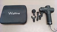 Wattne W1 massage gun with all five interchangeable heads and black carrying case on light background.